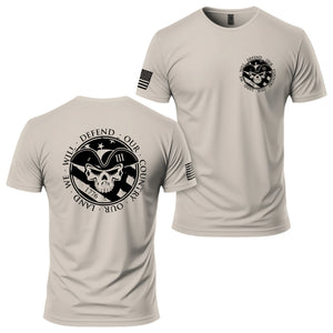 American Patriot T-Shirt in Sand, back and front: 1776 patriot skull seal reading WE WILL DEFEND OUR COUNTRY · OUR LAND printed large on the back, small matching seal on the left chest, American flag on the right sleeve