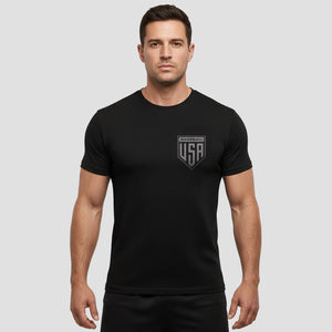 Man wearing a black t-shirt with a logo on a gray background