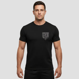 Man wearing a black t-shirt with a logo on a gray background