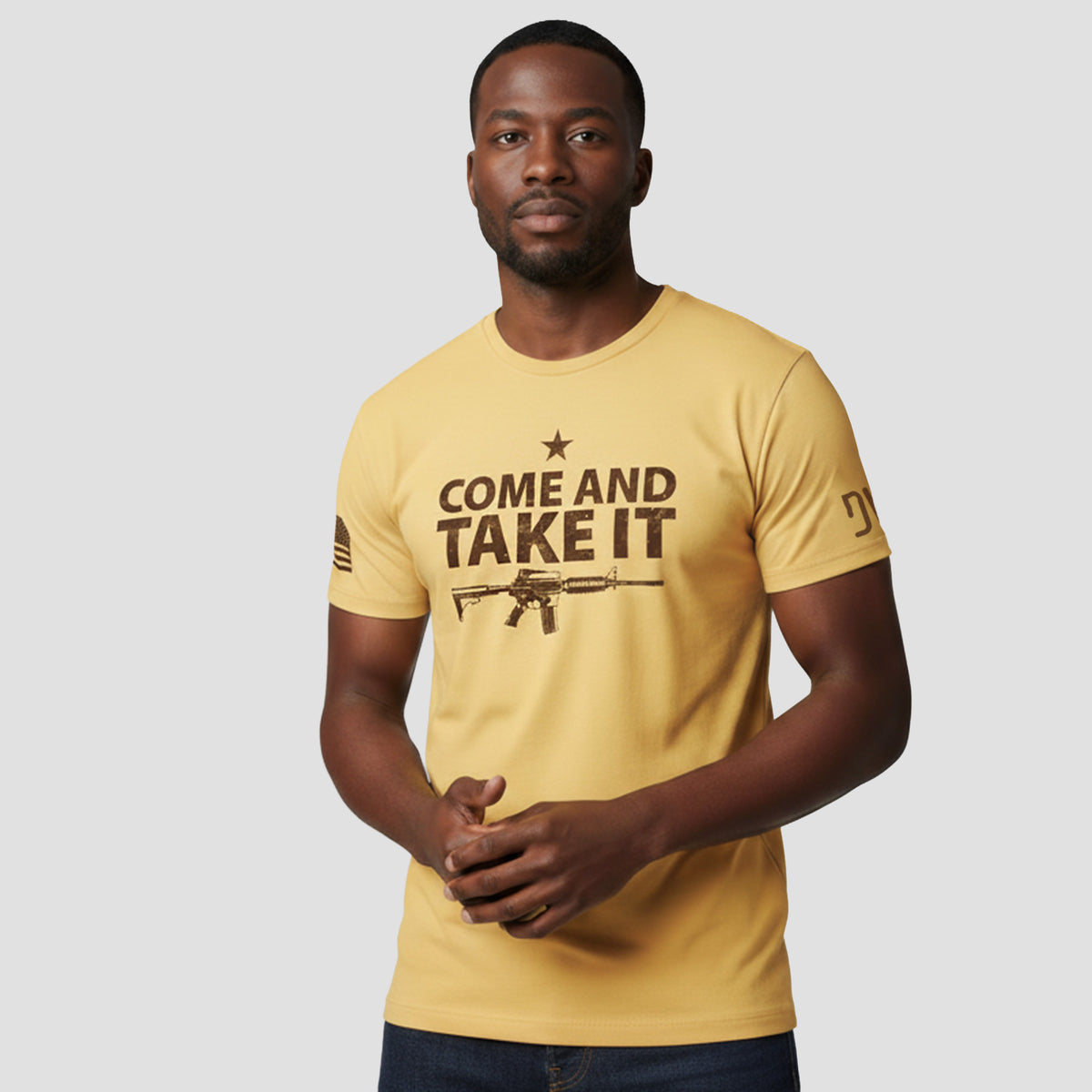 Man wearing a yellow t-shirt with 'COME AND TAKE IT' text and graphic on a gray background