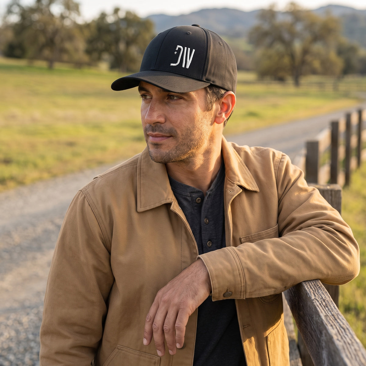 Man on a ranch road wearing the black Dion Wear Logo Stretch Fit Cap with the white 3D puff DW star monogram, front three-quarter view