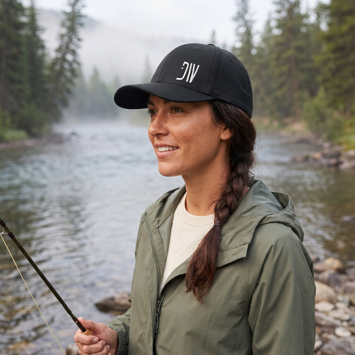 Woman fly fishing by a river wearing the black Dion Wear Logo Stretch Fit Cap: side three-quarter view of the structured crown, curved bill and white 3D puff DW star monogram