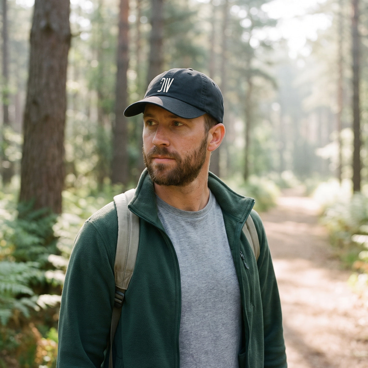 Hiker on a pine-forest trail in morning light wearing the black Dion Wear unstructured cap