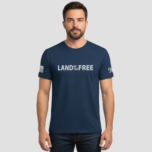 Man wearing a navy blue t-shirt with 'LAND OF THE FREE' text on a gray background